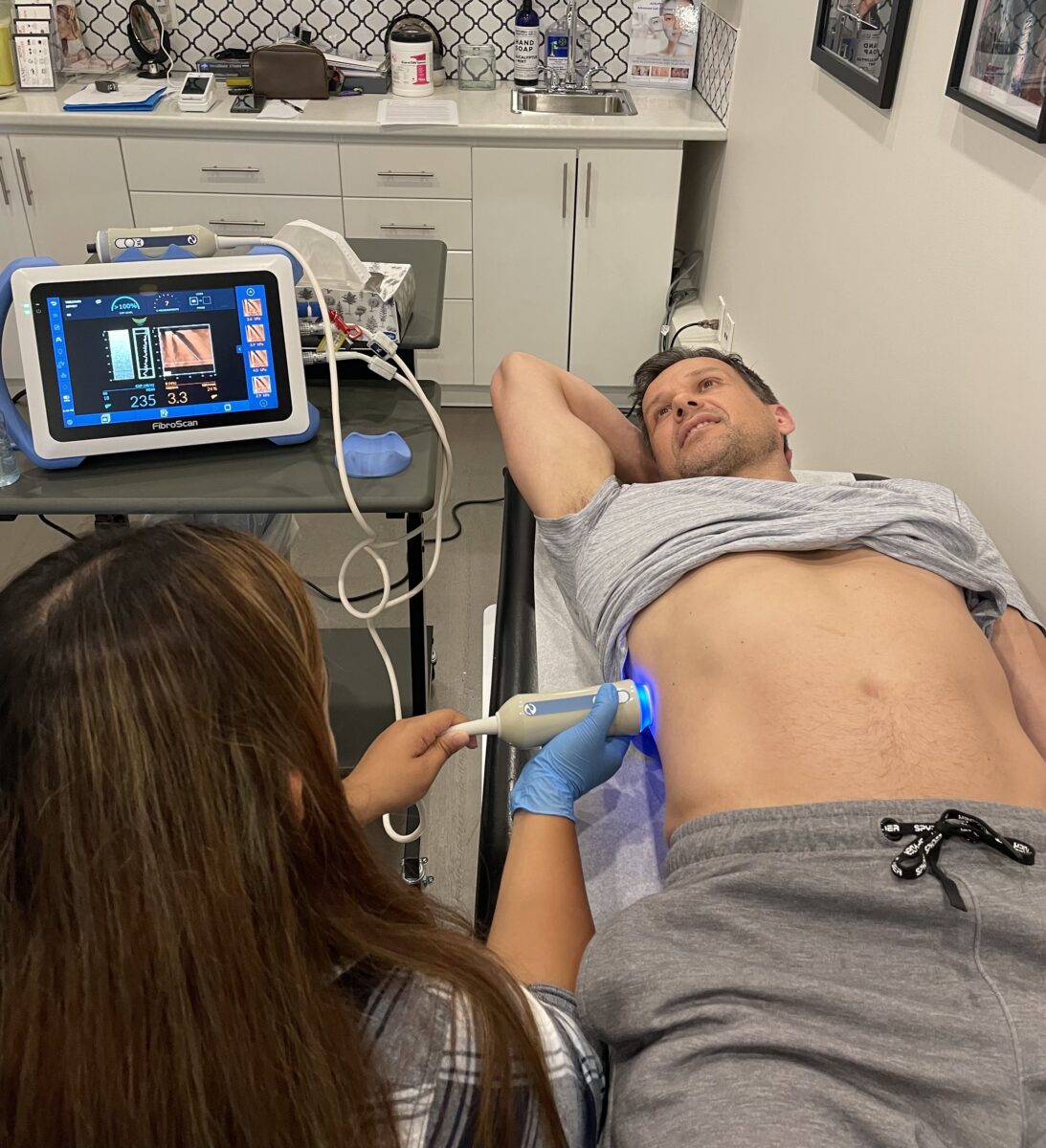 A man is laying on a bed with a machine on his stomach.