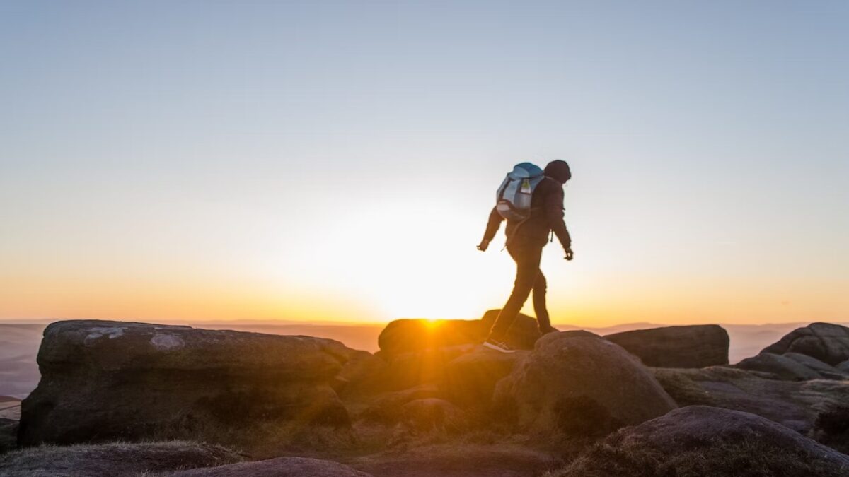 A person standing on top of a mountain at sunset.