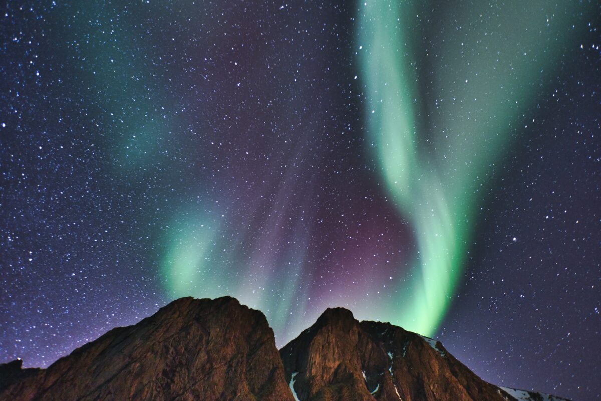 The aurora borealis lights up the sky over a mountain.