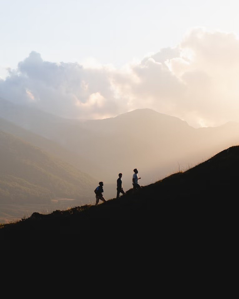 Silhouette of people running on a hill at sunset.